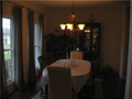 Viewed from Foyer, removed from kitchen by hall galley, invitational to guest via entry passage from living or family room, the formal dining area is vibrant from window coverings to wall color, has a tasteful hanging light fixture, hardwood floor